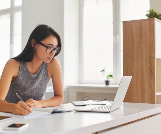 woman on laptop taking notes